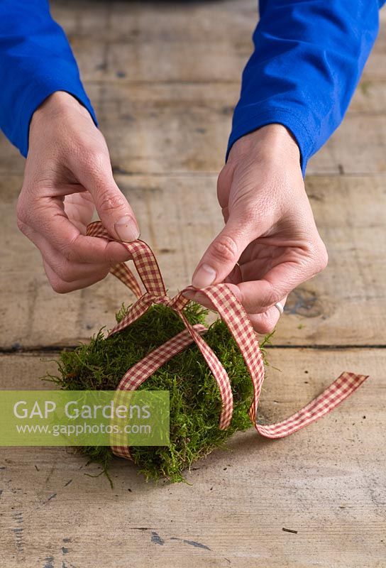 Step-by-step - tying ribbon around moss parcel - creating table decoration