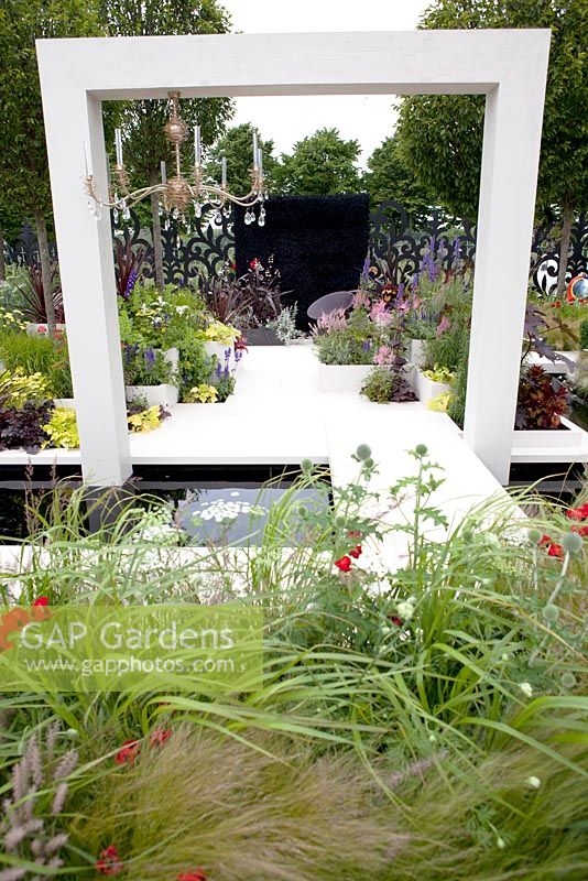 Contemporary arch. Planting of Astilbe chinenesis, Pennisetum orientalis, Cordyline 'Torbay Red', Heuchera 'Caramel' and 'Plum Pudding' in ceramic cladded planters. Russian Museum Garden. Hampton Court Palace Flower show 2012.