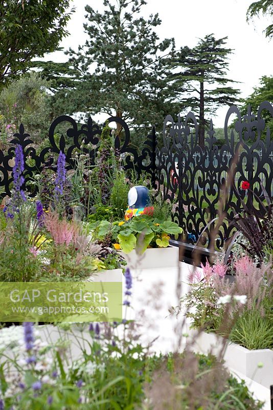 Astilbe chinenesis, Pennisetum orientalis, Cordyline 'Torbay Red', Heuchera 'Caramel' and 'Plum Pudding' in ceramic cladded planters. Russian Museum Garden. Hampton Court Palace Flower show 2012.