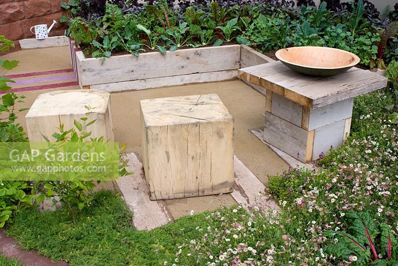 Raised vegetable beds and basic wooden cubed seats and table in the 'Growing Together' garden, RHS Tatton Flower Show 2012