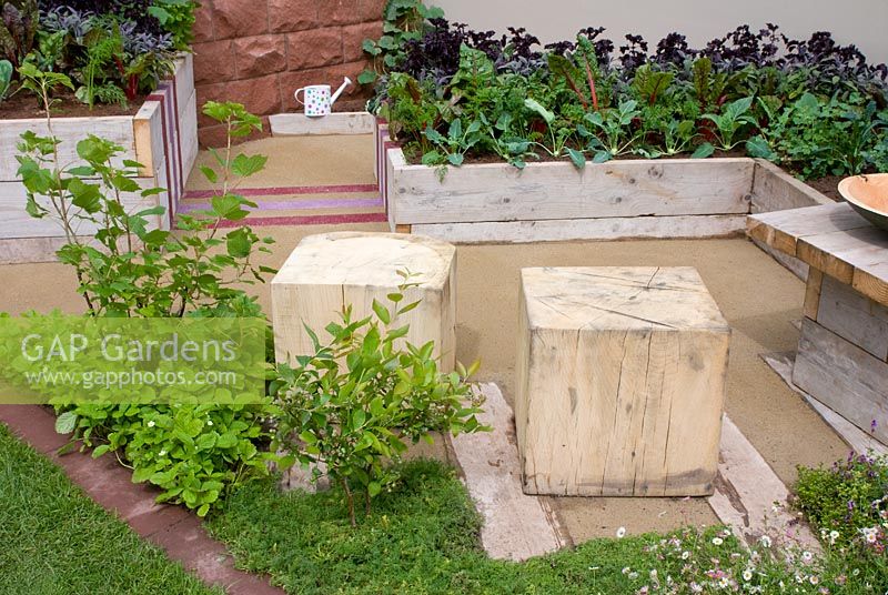 Raised vegetable beds, fruit bushes and basic wooden cubed seats and table in the 'Growing Together' garden, RHS Tatton Flower Show 2012