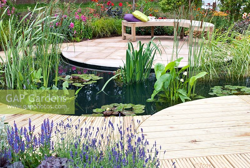 Central pond, surrounded by a decked path that leads to a seating area with sandstone paving and planting  that sweeps around the plot with Agapanthus, Cerinthe, Lavandula, Heuchera and Delphinium. 'A Taste of Ness' garden, RHS Tatton Flower Show 2012
