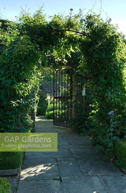Metal arch leading to gate with Yorkstone path 