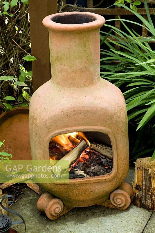 Terracotta chiminea with wood fire on patio