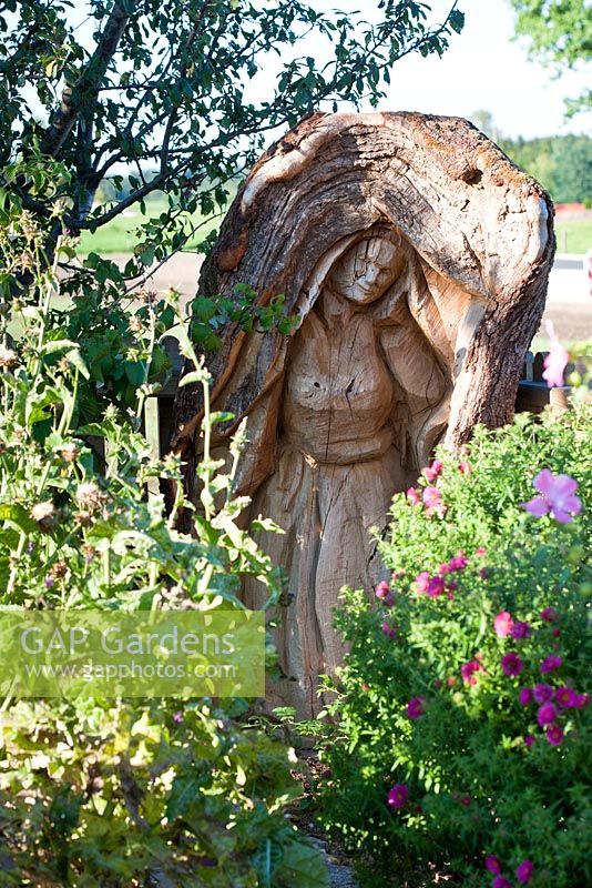 Wood sculpture of Maria, carved in a tree trunk with Asters