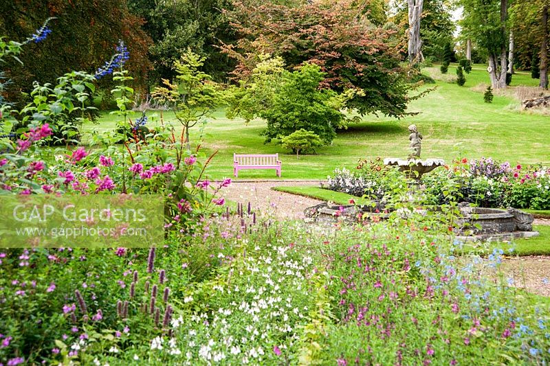 Fountain garden with beds full of salvias, zinnias, calendulas and other late season flowering plants, plus bench painted bright pink. Ragley Hall, Alcester, Warwickshire, UK
