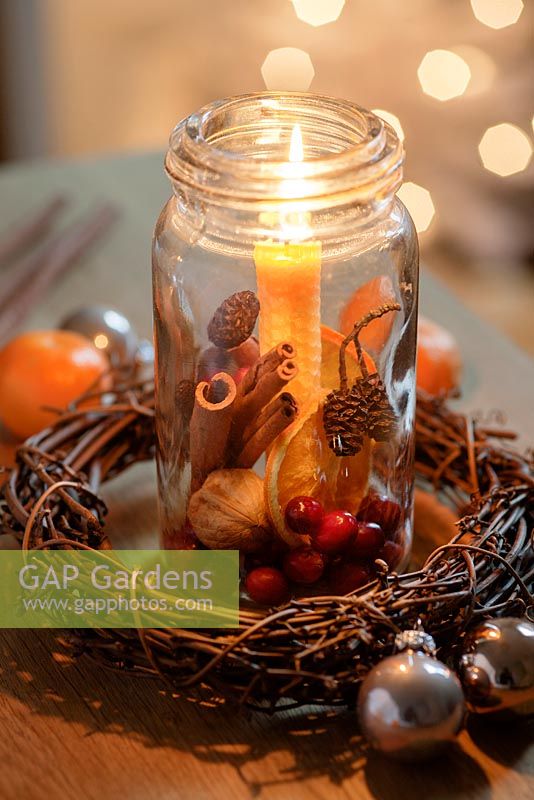 Old glass jars filled with cranberries, cinnamon sticks, dried orange slices, walnuts and larch scones with a beeswax candle