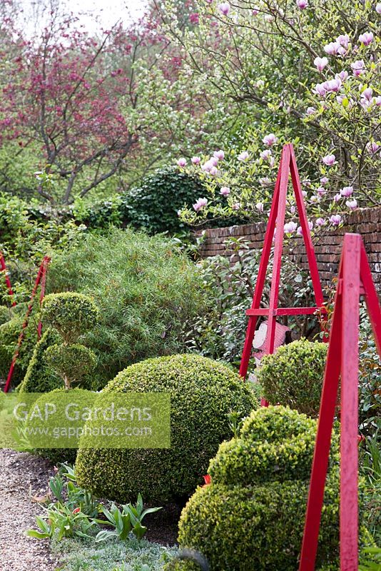 Decorative obelisks and topiary shapes in The Alice Garden in spring - West Green House, Hampshire