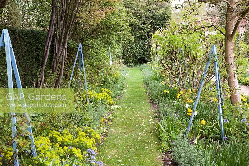 Decorative obelisks in spring garden - West Green House, Hampshire