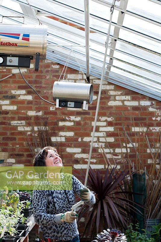Woman manually opening the roof of a greenhouse