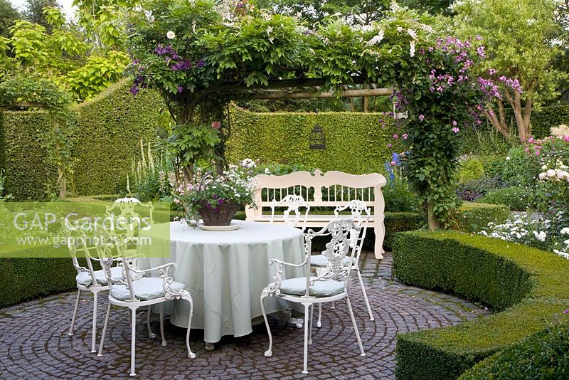 Formal seating area on paved terrace and clipped box hedges