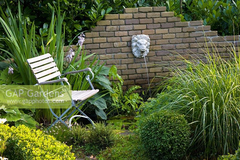 Relaxing area near the pond with a wall mounted water feature