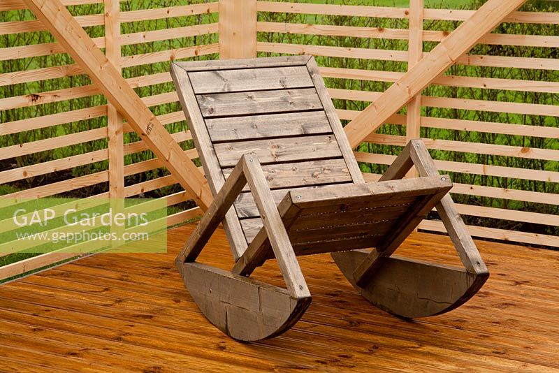 Wooden rocking chair in corner of garden 