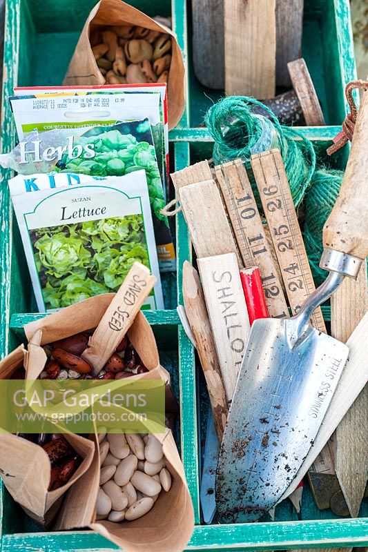Spring time potting bench with wooden tray of gardening items including packets of seeds, wooden labels and garden twine