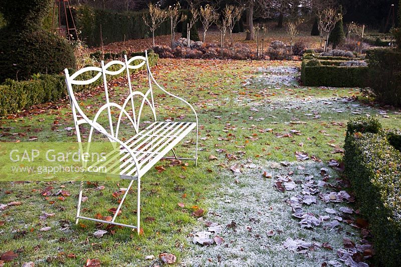 Decorative metal bench overlooking formal Topiary Garden in winter - The Old Rectory, Surrey