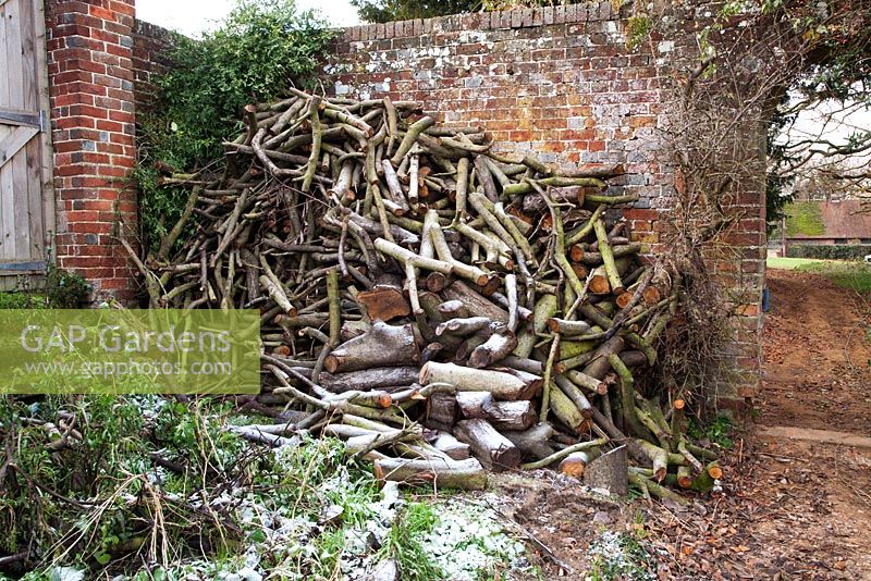 Log pile store in winter in walled garden - The Old Rectory, Surrey