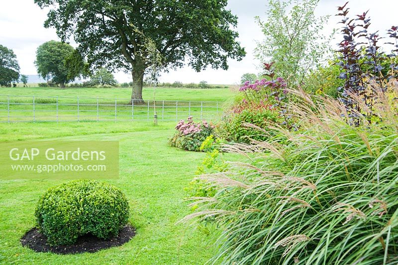 Park fencing gives an airy border between garden and surrounding fields - Rhodds Farm, Kington, Herefordshire, UK