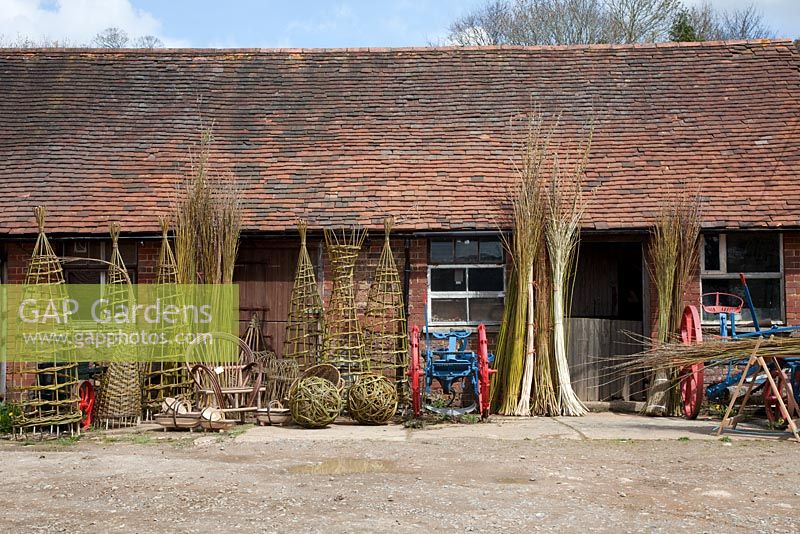 Display of finished woven willow plant supports, baskets, trugs and spheres by weaver Dominic Parrette - Sussex Willow