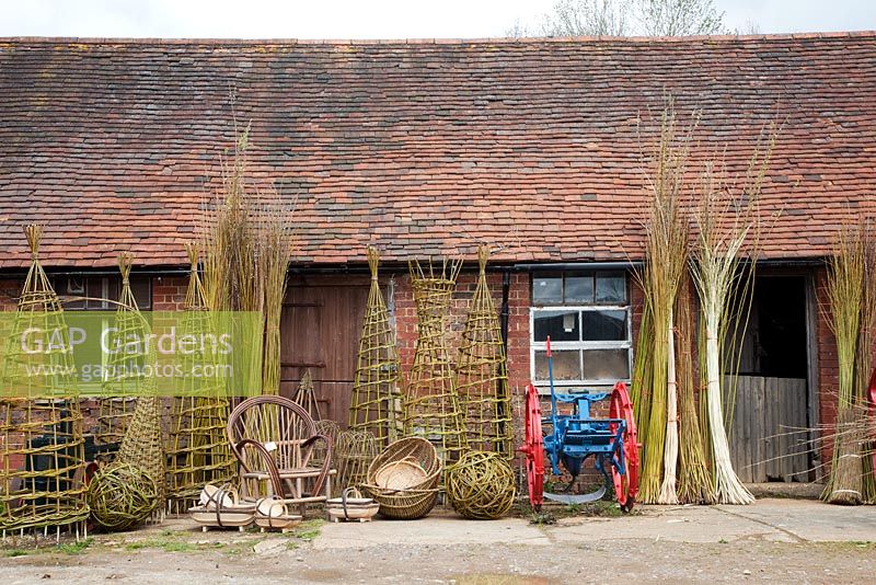 Display of finished woven willow plant supports, baskets, trugs and spheres by weaver Dominic Parrette - Sussex Willow
