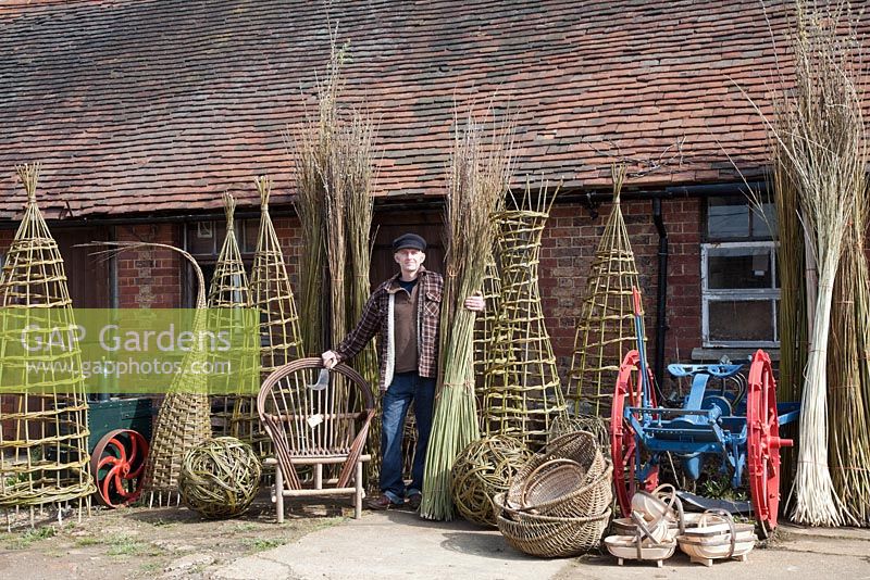 Willow weaver Dominic Parrette with a variety of his creations, plants supports, sculptural sphere, Gypsy chair, trugs and baskets - Sussex Willow 