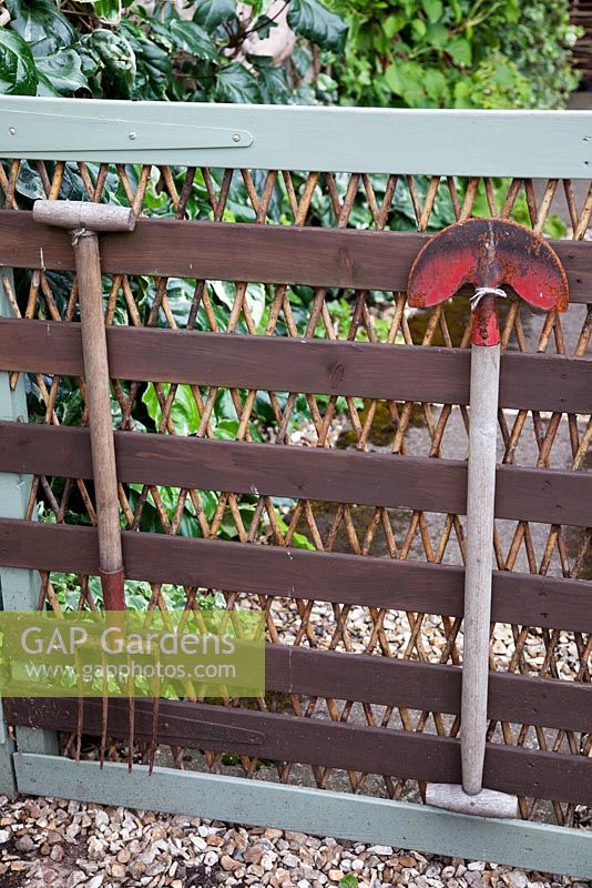 Painted wooden gate decorated with vintage garden tools, leading to vegetable garden. Garden Neighbours
