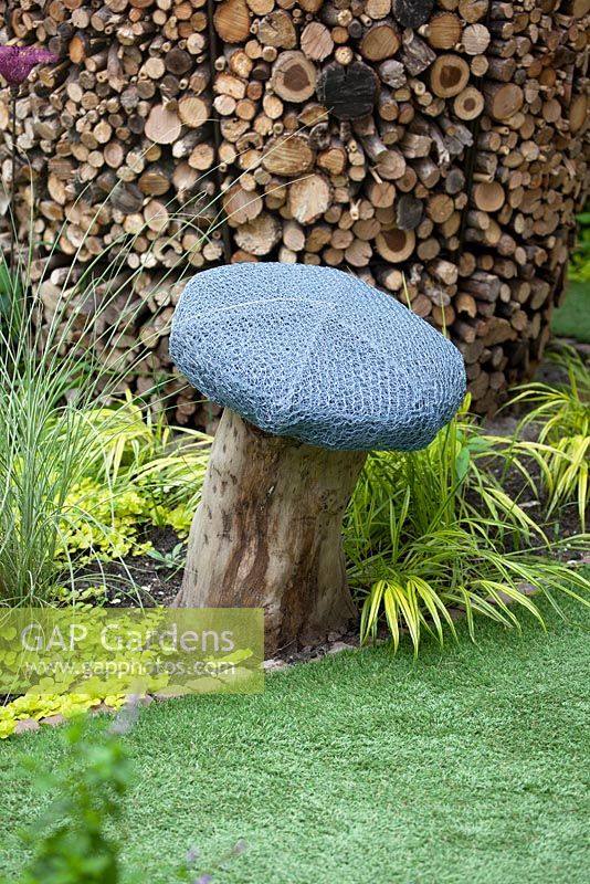 Seat in shape of mushroom made from chicken wire and tree trunk and artificial grass in modern courtyard garden 