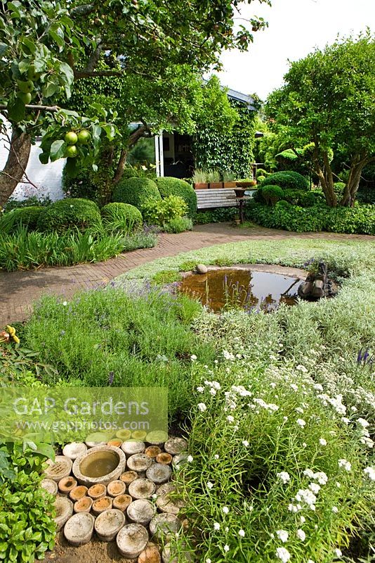 Ceramic birdbath and pond surrounded by planting of Lavender, Anaphalis, Antennaria dioica, Apple and Plum trees, Buxus and Taxus topiary and hedges, Artemisia 'Silver queen', Brunnera, Lavender, Veronica spicata and Bamboo - Ulla Molin