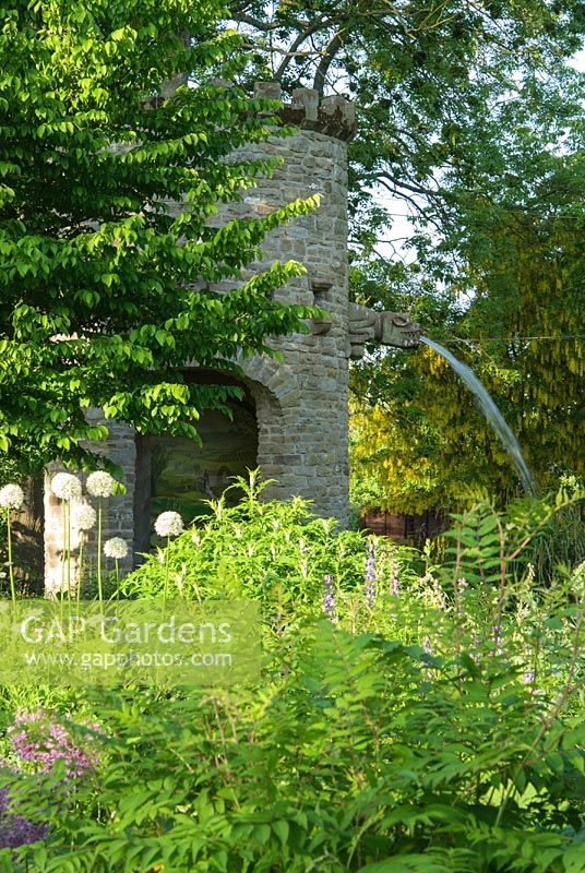 Stone dovecot that operates as a spectacular water feature as well. A simple belt and trough system scoops water up from the mill leat into a tank which, when full spouts throught the open mouth of a gargoyle back into the mill pond - Westonbury Mill
