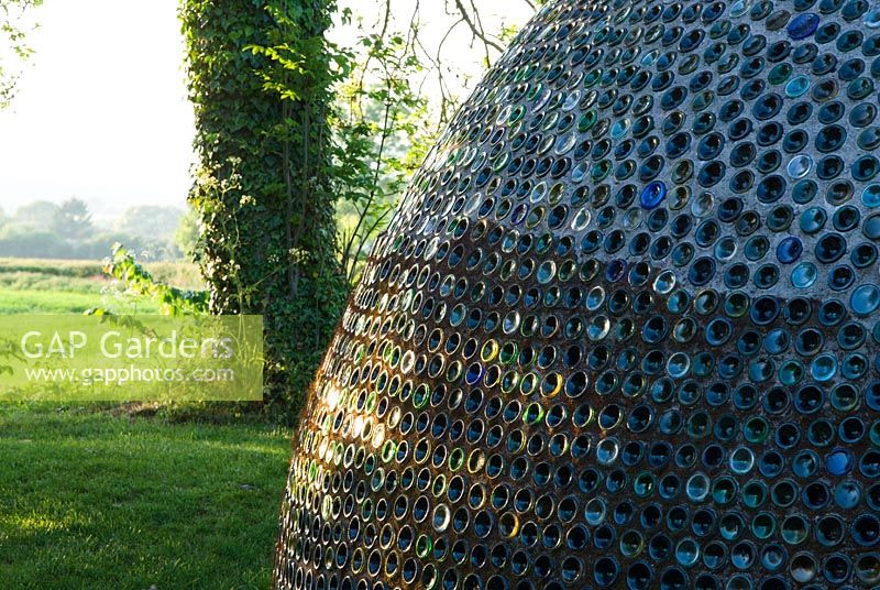 Dome structure made from thousands of bottles, with countryside beyond - Westonbury Mill