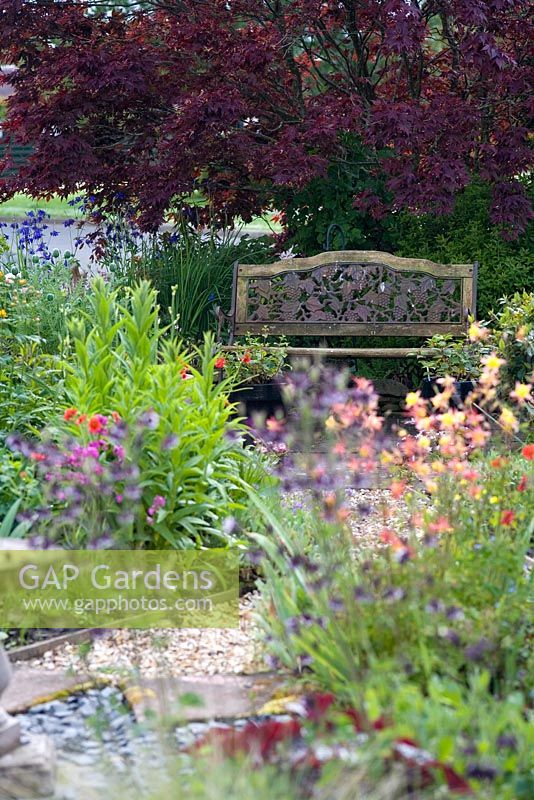 View through summer planting to ornate bench