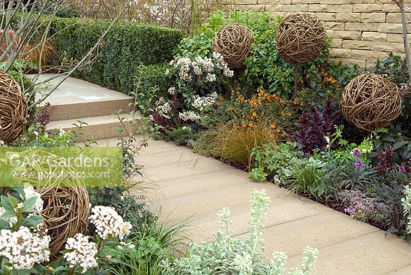Path and steps with well stocked borders of shrubs, perennial plants and modern architectural features - 'The Rough with the Smooth' Show Garden, Premier Gold Award, Harrogate Spring Flower Show 2013