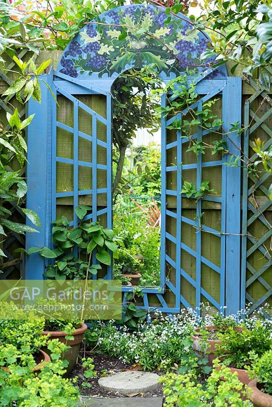 Garden mirror feature with blue painted surround with 'Green man' themed painting at top