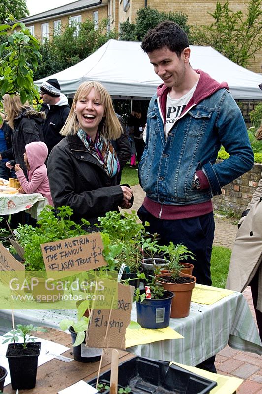 Young couple buying plants from stall at King Henry's Walk Garden, urban community allotments, London Borough of Islington, UK