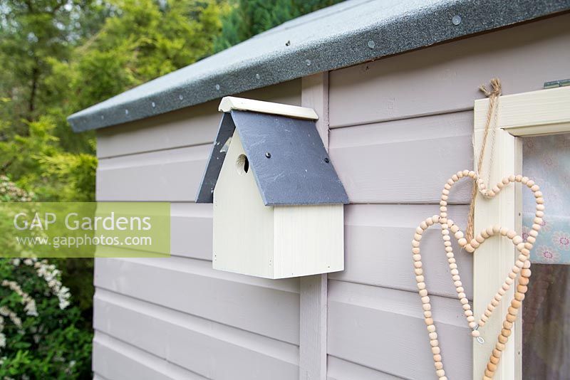 Freshly painted birdbox hanging on shed

