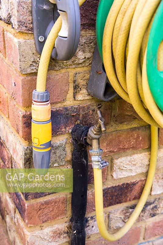 Garden hose mounted on the side of house