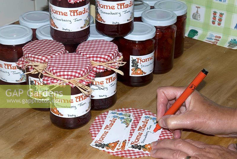 Making Strawberry jam - writing labels and placing attractive red gingham tops on jars tied with rafia 