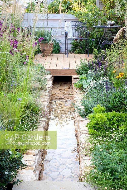 Modern water feature and planting of Salvia, Achillea, Calamagrostis acutiflora 'Waldenbuch' and Stipa tenuissima