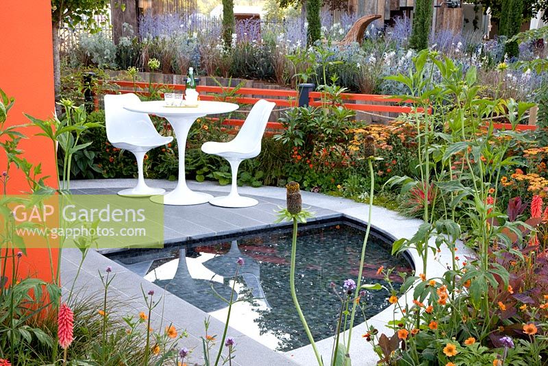Modern garden with pond and furniture - planting includes Achillea Terracotta