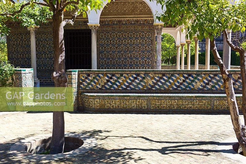 The Pavilion of Carlos V. Walls and seats decorated with Azulejos tiles in The Abode Garden with Seville Orange trees Citrus aurantium at El Real Alcázar de Sevilla Andalusia, Spain