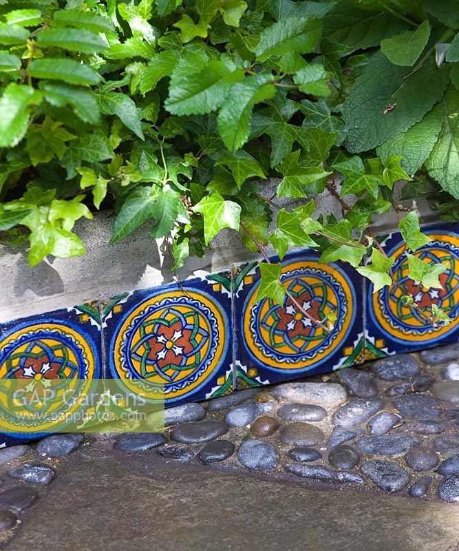 Decorative edging made from colourful tiles. Small town garden, Brighton, UK 