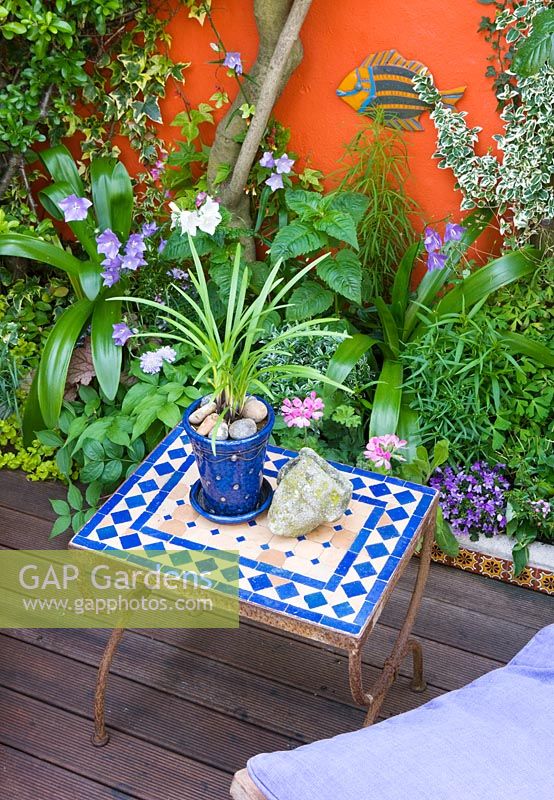 Mosaic Moroccan table in small garden with painted walls and decking, Brighton, UK 