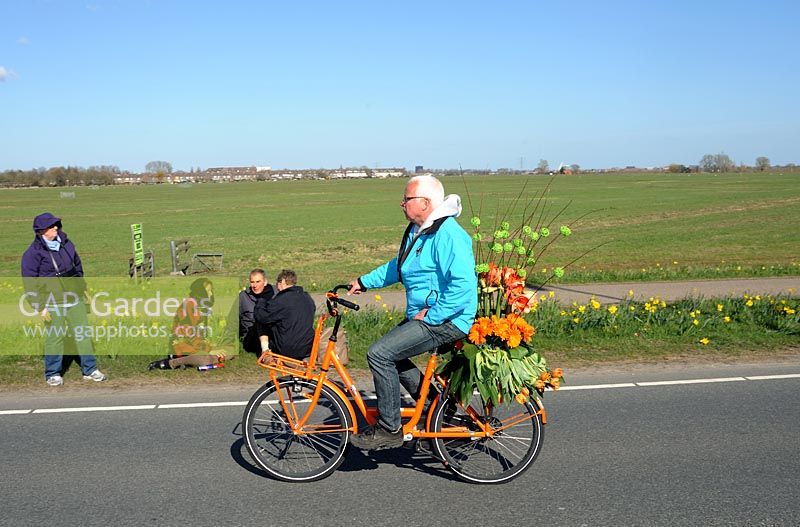 Parade co-ordinator on a bicycle with flowers decorated bike. 