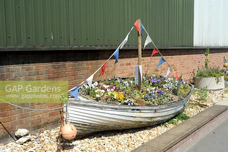 Old boat filled with flowers adds interest to an industrial area. 