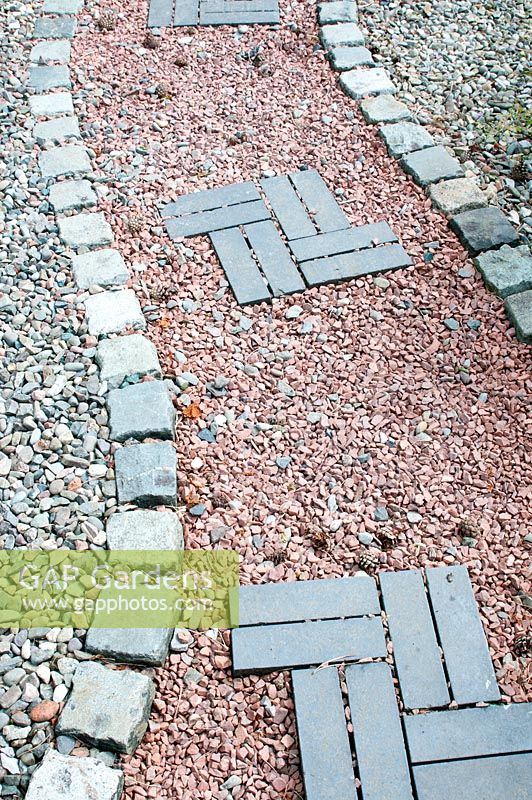 Attractive garden path made of ornamental gravel cobble setts and blue slate bricks