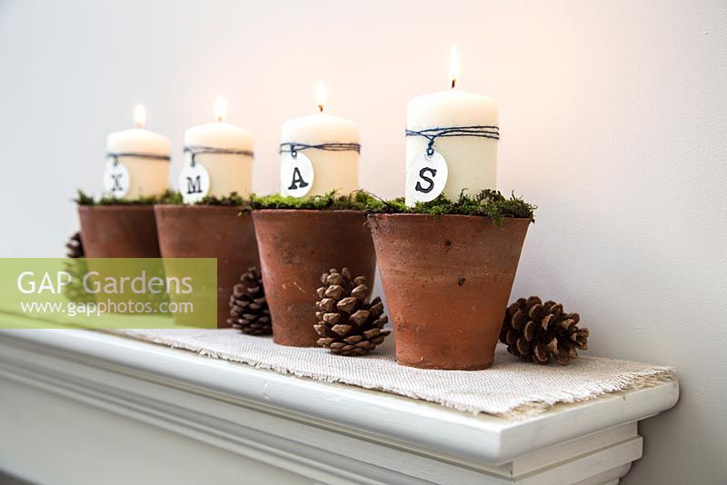 Christmas candle decorations spelling XMAS, made using terracotta pots and moss
