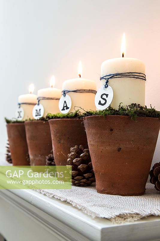 Christmas candle decorations spelling XMAS, made using terracotta pots and moss