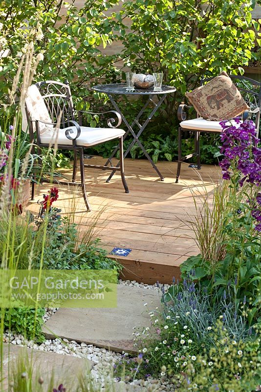 Table and chairs on decking. Penstemon Raven, Dahlia, Stipa tenuissima, Lavender. 