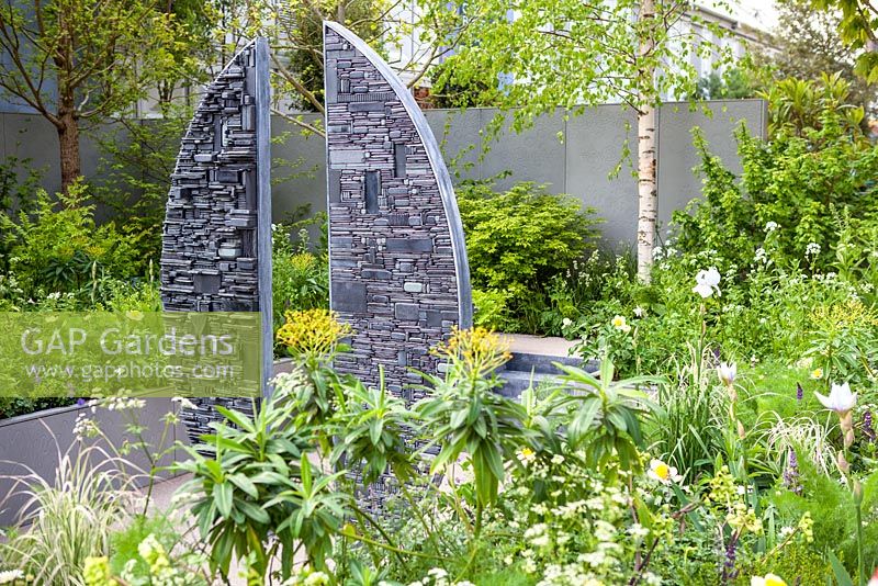 Slate sculpture by Tom Stogdon set in sunken garden with surrounding borders