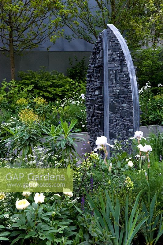 Slate sculpture by Tom Stogdon set in sunken garden with surrounding borders
