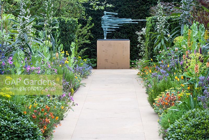 Flowering borders including Echium pininana, Geranium maderense and Geum with pathways and sculpture in The Lucid Garden in The Arthritis Research UK Garden
